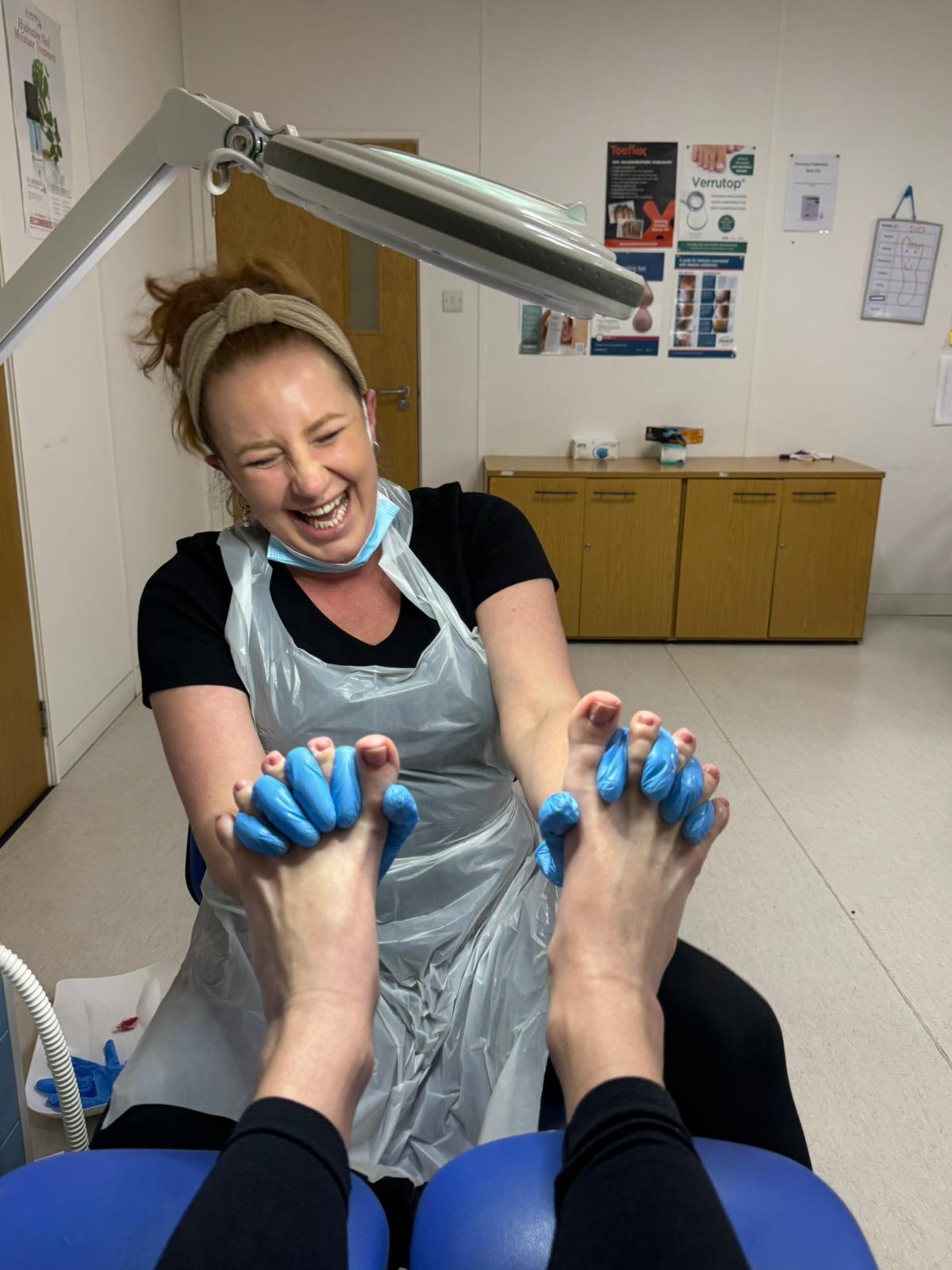 Michelle laughing warmly with a patient during a foot care appointment